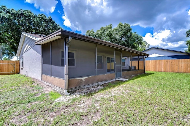 rear view of property featuring a yard and a sunroom