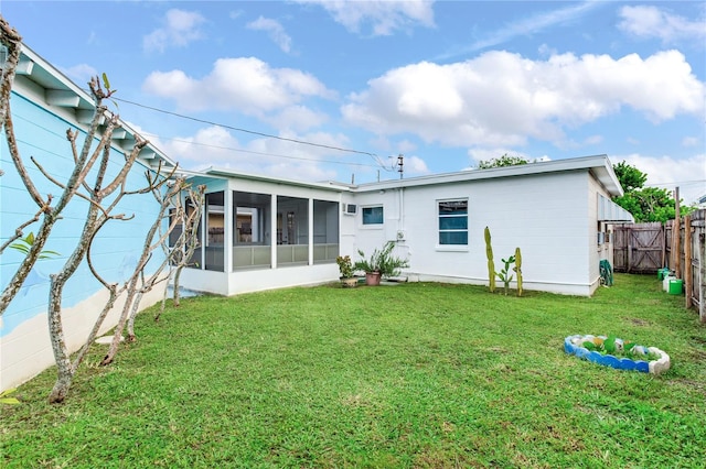 rear view of house with a sunroom and a yard