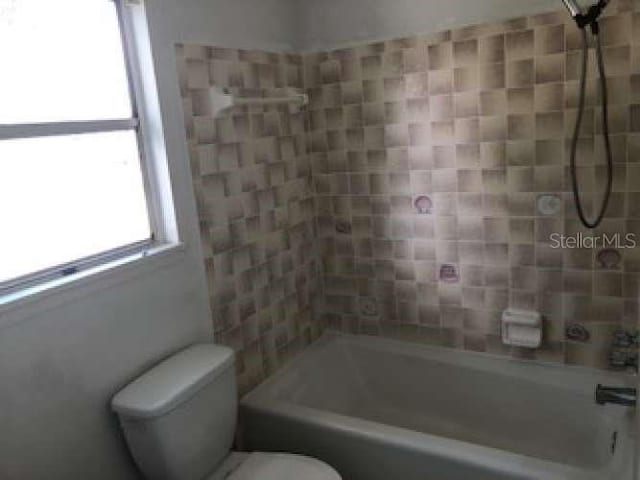 bathroom featuring tiled shower / bath combo and toilet