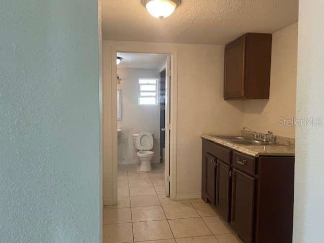 bathroom featuring tile patterned flooring, vanity, toilet, and a textured ceiling