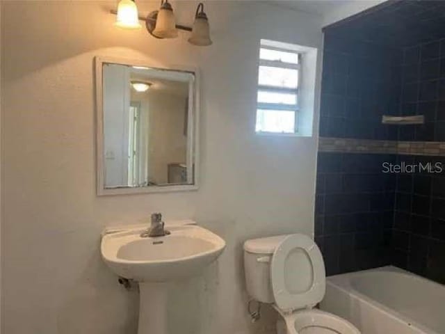 bathroom with tiled shower / bath combo and toilet