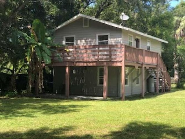 rear view of house with a wooden deck and a lawn