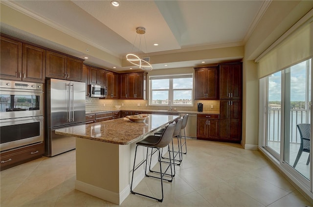 kitchen featuring light stone countertops, sink, a center island, hanging light fixtures, and appliances with stainless steel finishes