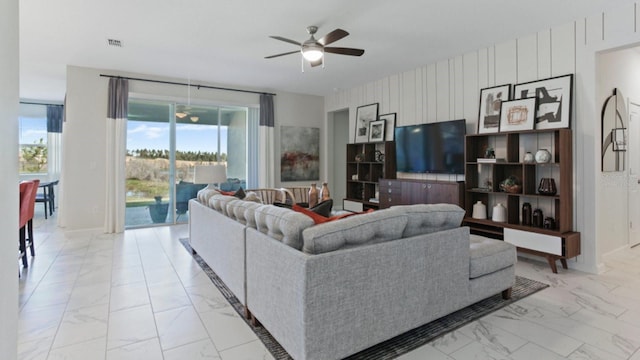 living room with ceiling fan and wood walls