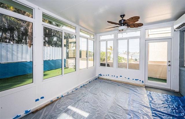 unfurnished sunroom with a wall mounted air conditioner and ceiling fan