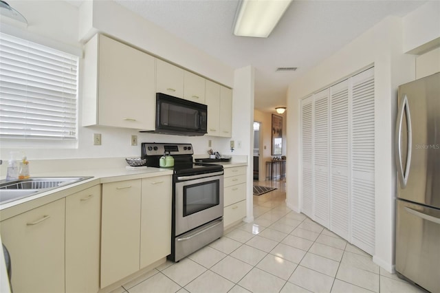 kitchen with cream cabinets, light tile patterned flooring, and appliances with stainless steel finishes