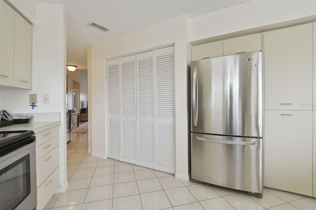 kitchen with cream cabinetry, light tile patterned floors, and appliances with stainless steel finishes