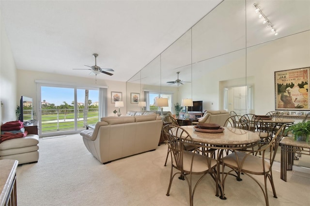 dining space with lofted ceiling, rail lighting, light colored carpet, and a healthy amount of sunlight