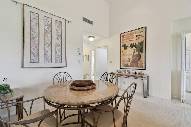 dining space featuring light carpet and a towering ceiling