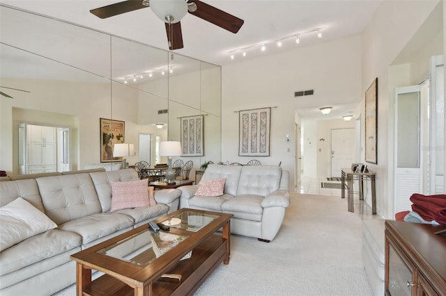 carpeted living room with ceiling fan and a high ceiling