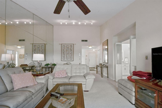 living room featuring carpet flooring, ceiling fan, and a high ceiling