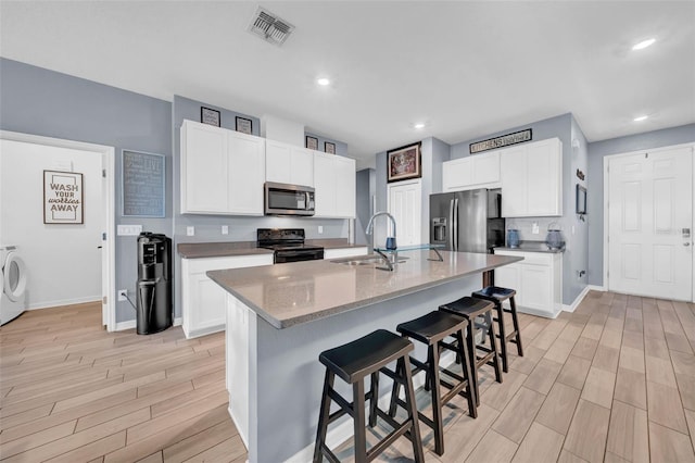 kitchen with sink, stainless steel appliances, a kitchen bar, a kitchen island with sink, and white cabinets