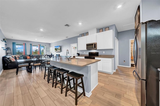 kitchen featuring white cabinets, sink, a breakfast bar area, an island with sink, and stainless steel appliances