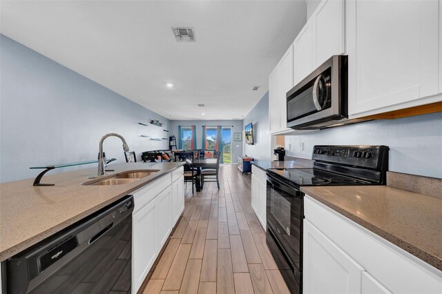 kitchen with light stone countertops, sink, white cabinets, and black appliances