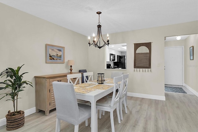 dining space featuring light hardwood / wood-style flooring, a textured ceiling, and an inviting chandelier