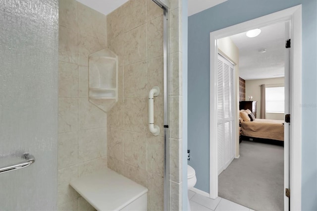 bathroom featuring tile patterned floors, toilet, and a shower with shower door