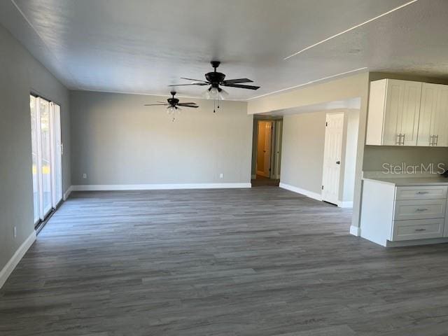 unfurnished living room featuring dark hardwood / wood-style flooring and ceiling fan