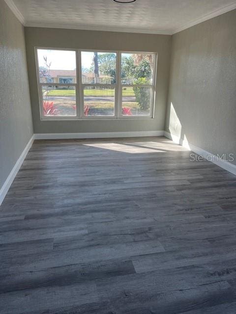 spare room featuring crown molding and dark wood-type flooring