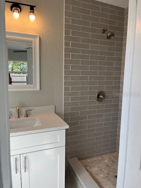 bathroom with vanity and a tile shower