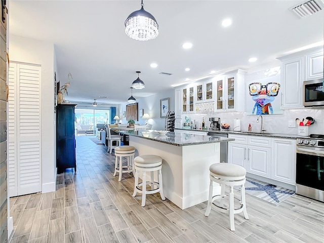 kitchen with pendant lighting, appliances with stainless steel finishes, a breakfast bar area, and white cabinets