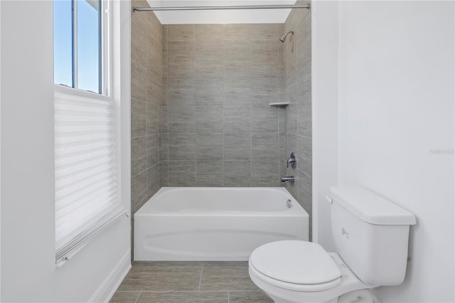 bathroom with toilet and tiled shower / bath