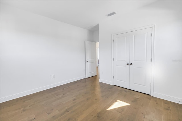 unfurnished bedroom featuring a closet and hardwood / wood-style flooring