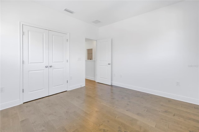 unfurnished bedroom with light hardwood / wood-style flooring and a closet