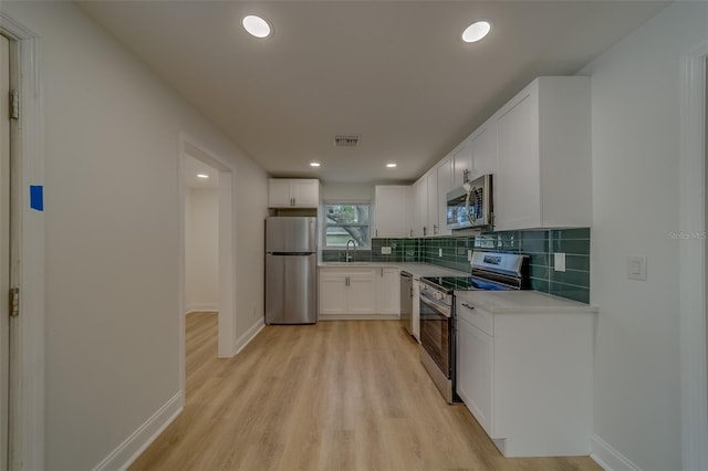 kitchen featuring sink, white cabinetry, stainless steel appliances, tasteful backsplash, and light hardwood / wood-style floors