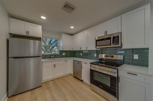 kitchen with white cabinetry, sink, light hardwood / wood-style flooring, and stainless steel appliances