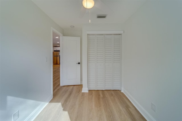 unfurnished bedroom with stainless steel fridge, a closet, and light wood-type flooring