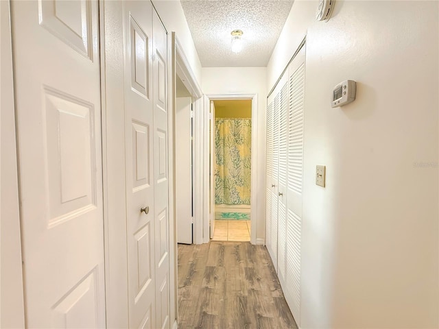 corridor with wood-type flooring and a textured ceiling