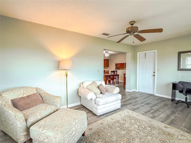 living room featuring hardwood / wood-style floors, a textured ceiling, and ceiling fan