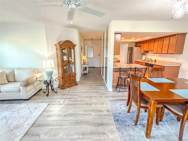 dining space with ceiling fan, light hardwood / wood-style flooring, and a textured ceiling