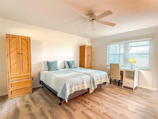 bedroom with ceiling fan, hardwood / wood-style flooring, and a textured ceiling