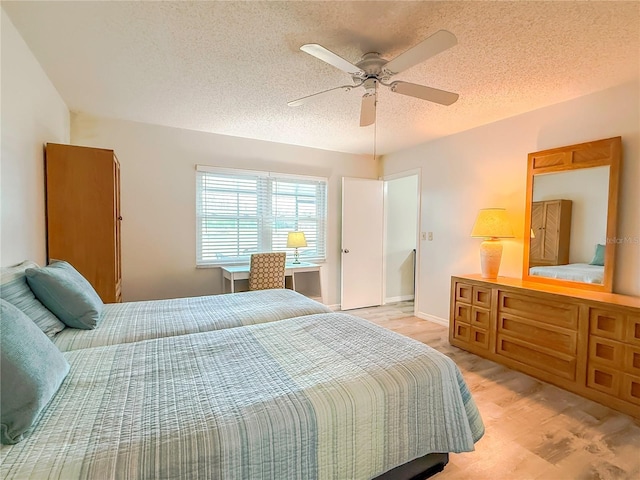 bedroom with ceiling fan, light hardwood / wood-style flooring, and a textured ceiling