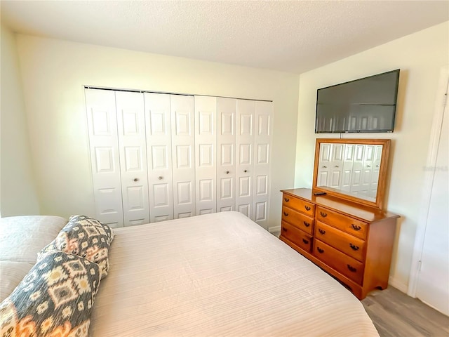 bedroom with hardwood / wood-style floors, a closet, and a textured ceiling