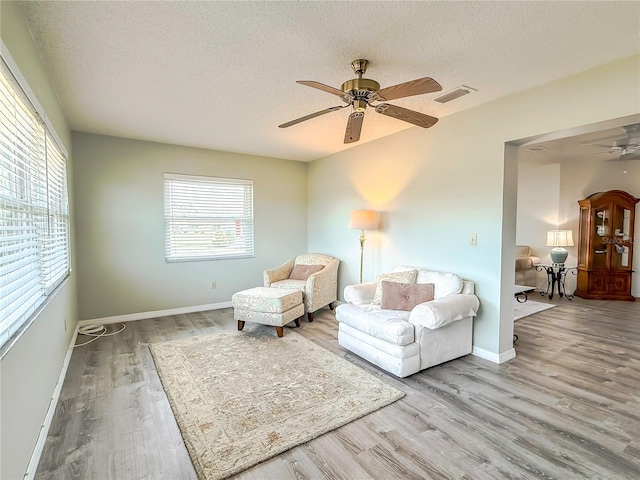 sitting room with ceiling fan, light hardwood / wood-style floors, and a textured ceiling