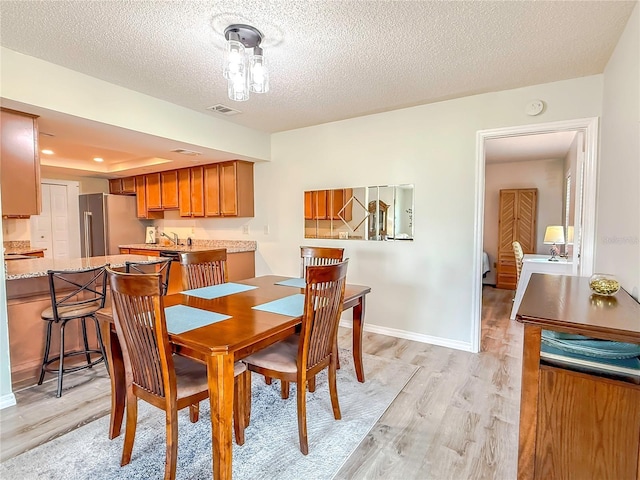 dining room featuring light hardwood / wood-style floors and a textured ceiling