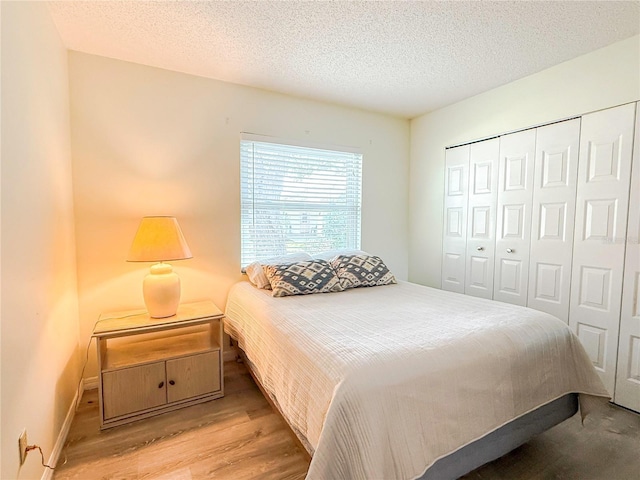 bedroom with light hardwood / wood-style floors, a closet, and a textured ceiling