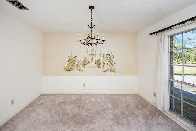 carpeted spare room with a chandelier and a textured ceiling