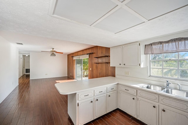 kitchen with ceiling fan, sink, dark wood-type flooring, kitchen peninsula, and white cabinets