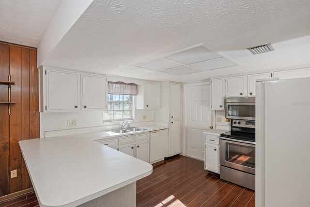 kitchen featuring sink, white cabinetry, stainless steel appliances, and wooden walls