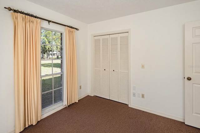 unfurnished bedroom with dark colored carpet and a closet