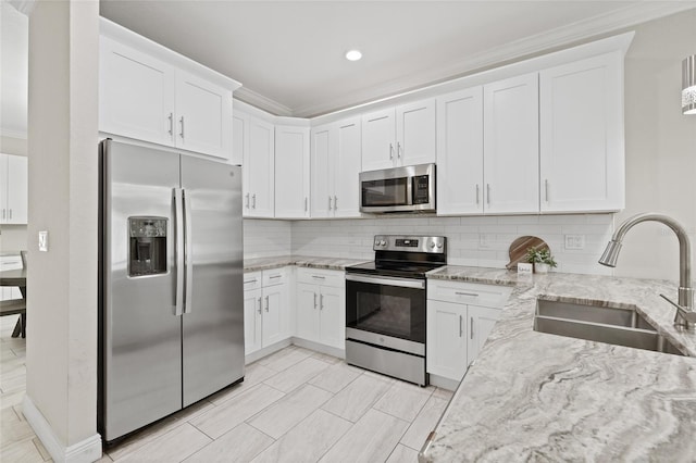 kitchen featuring white cabinets, appliances with stainless steel finishes, light stone countertops, and sink