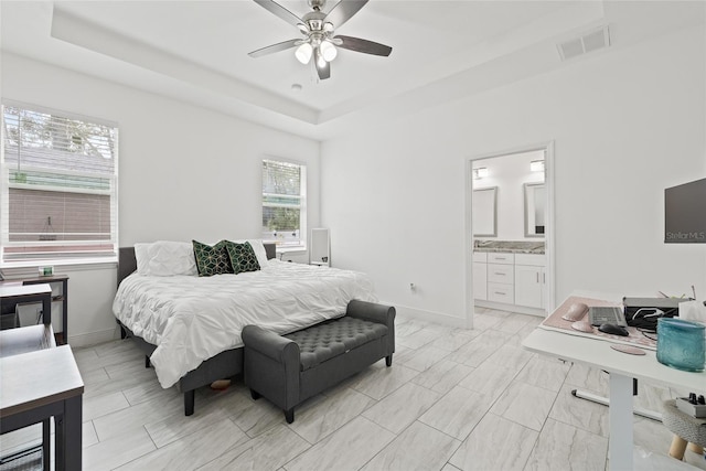 bedroom featuring ceiling fan, a raised ceiling, and ensuite bath