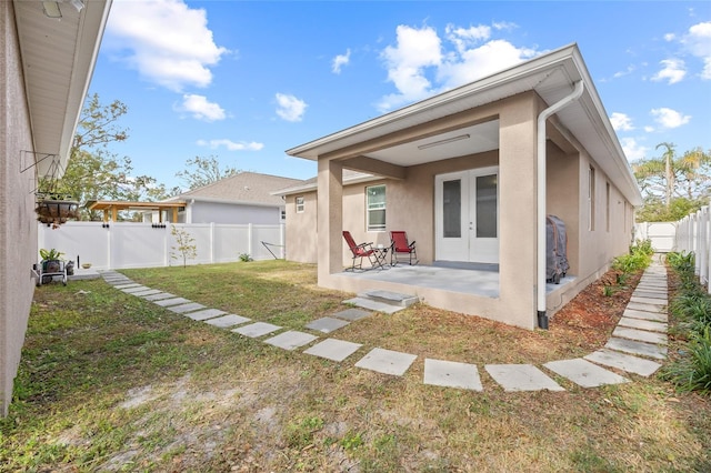 rear view of property with a lawn, a patio area, and french doors