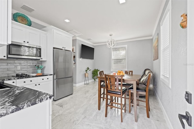 kitchen featuring white cabinets, pendant lighting, backsplash, and appliances with stainless steel finishes