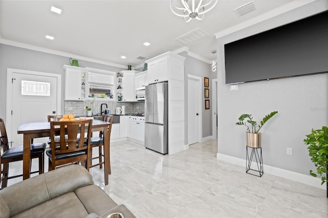 interior space with tasteful backsplash, crown molding, white cabinets, and appliances with stainless steel finishes