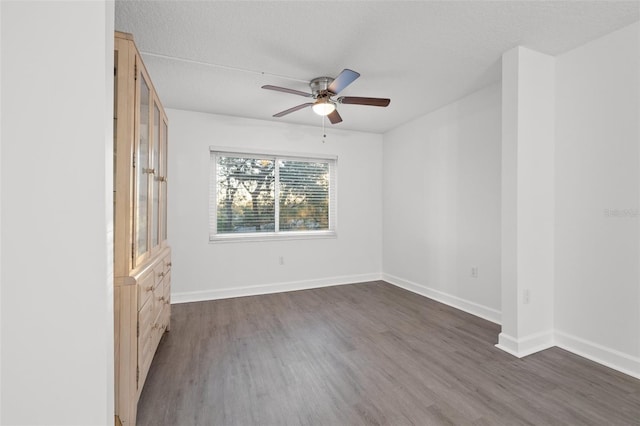 unfurnished room with a textured ceiling, ceiling fan, and dark wood-type flooring