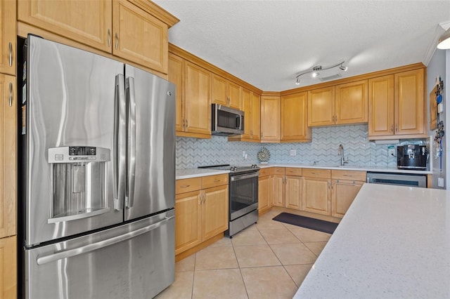 kitchen featuring backsplash, light tile patterned flooring, stainless steel appliances, and a textured ceiling